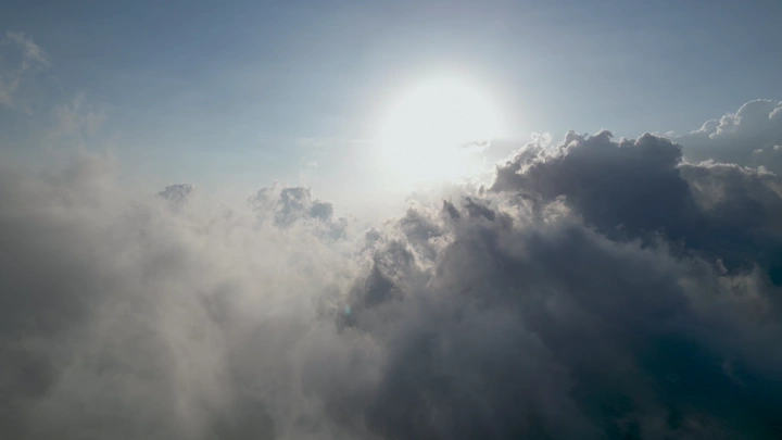 مشهد للغيوم تحت الشمس من درون، لقطة جوية.