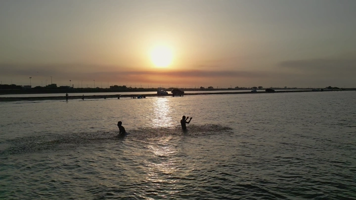 شباب يلعبون في ساحل البحر الأحمر عند الغروب، لقطة طبيعية.