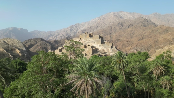 Dhee Ayn village in Al-Baha, drone shot showing mountains and palm trees.