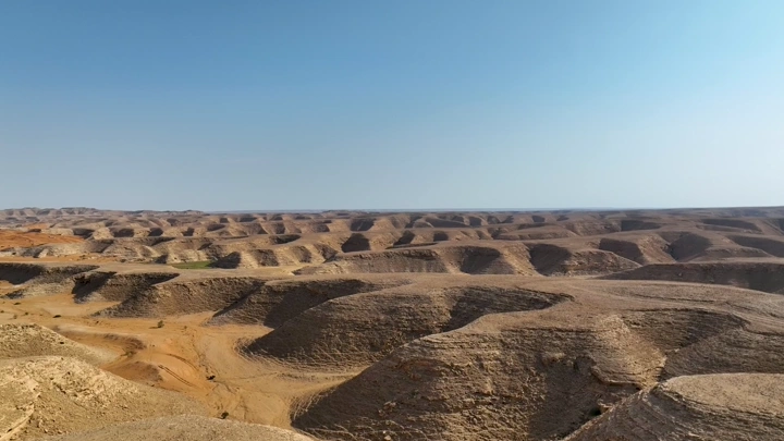 تضاريس جبلية وصحراوية تحت سماء زرقاء، لقطة جوية.