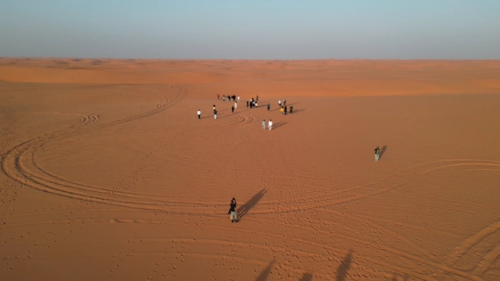 مجموعة أشخاص يتجولون في صحراء النفود، لقطة جوية.