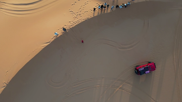 مجموعة شباب في الصحراء مع سيارة، لقطة جوية.