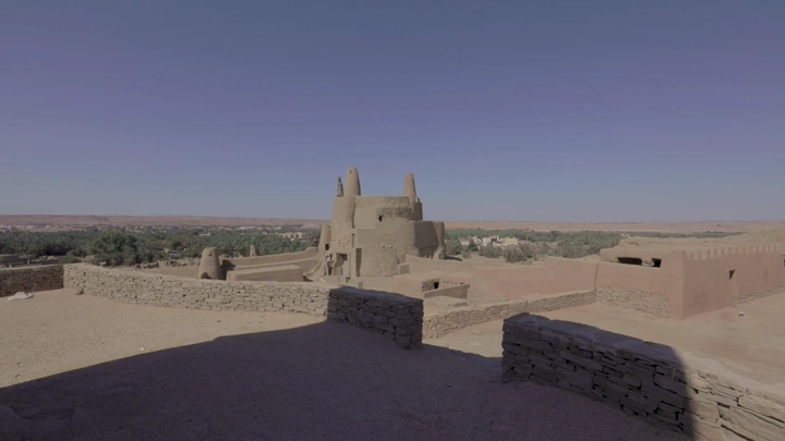 قلعة طينية في دومة الجندل تحت سماء صافية، لقطة واسعة.