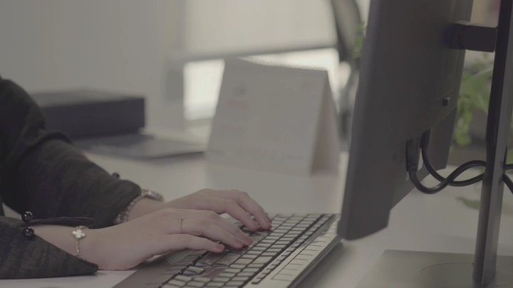 يدان تكتبان على لوحة مفاتيح في مكتب، لقطة مقربة.