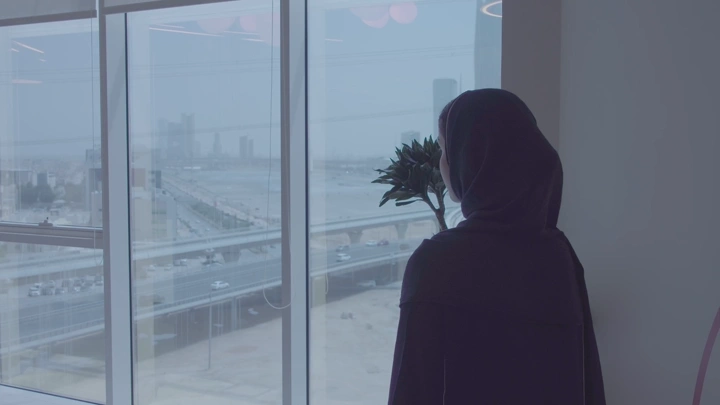 امرأة تنظر إلى المركز المالي من نافذة، لقطة داخلية.