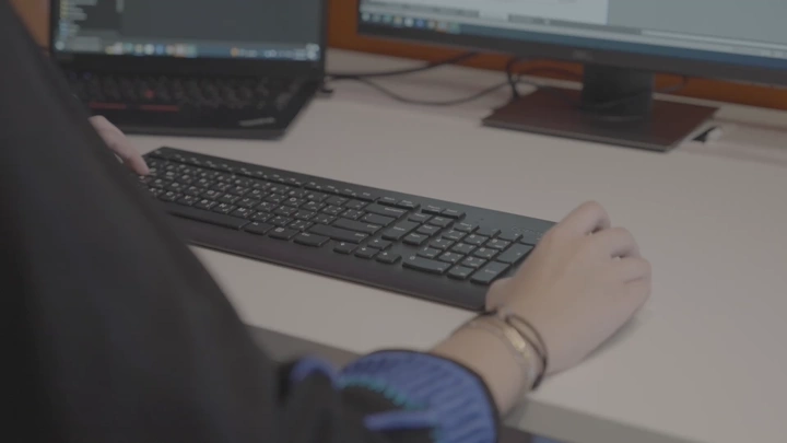 فتاة تعمل على الكمبيوتر في مكتب، لقطة قريبة.