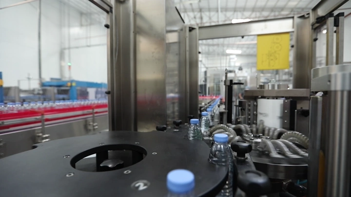 خط إنتاج زجاجات مياه في مصنع، لقطة داخلية.