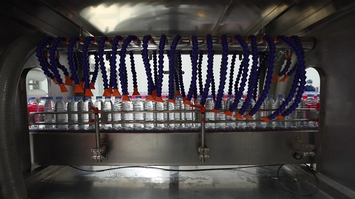 خط إنتاج زجاجات مياه في مصنع، لقطة داخلية.