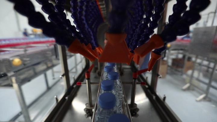 خط إنتاج زجاجات مياه في مصنع، لقطة مقربة.
