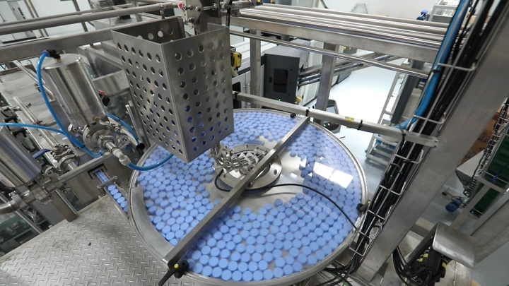 آلة تعبئة زجاجات في مصنع مياه، لقطة من الأعلى.