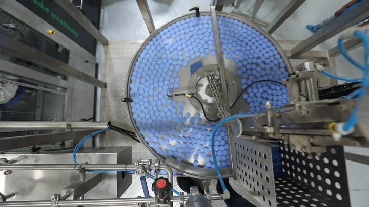 آلة تعبئة زجاجات في مصنع مياه، لقطة من الأعلى.