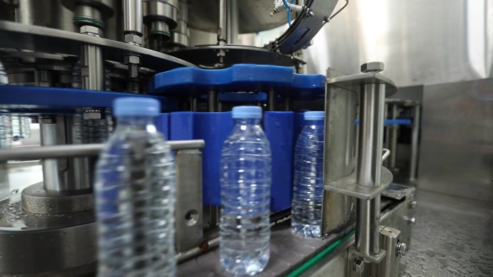 زجاجات مياه على خط إنتاج في مصنع، لقطة مقربة.