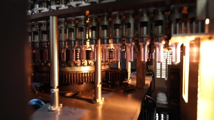 آلة تعبئة زجاجات في مصنع مياه، لقطة مقربة.