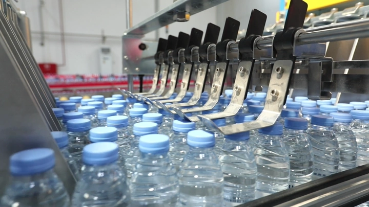 خط إنتاج زجاجات مياه في مصنع، لقطة مقربة.