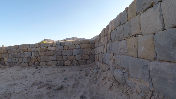 جدار حجري في الأخدود نجران تحت سماء صافية، لقطة بزاوية منخفضة.
