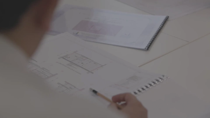 شخص يراجع مخطط معماري على طاولة، لقطة مقربة.