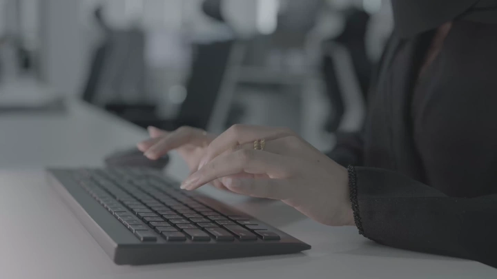 يد فتاة تكتب على لوحة مفاتيح في مكتب، لقطة قريبة.