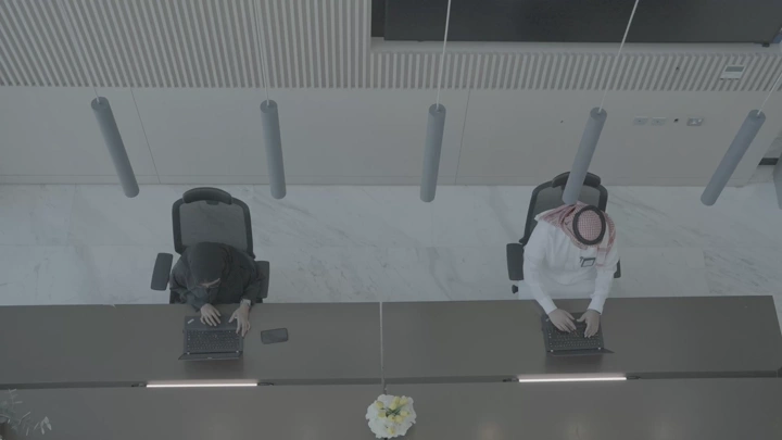 موظفو استقبال سعوديون في مكتب حديث، لقطة من الأعلى.