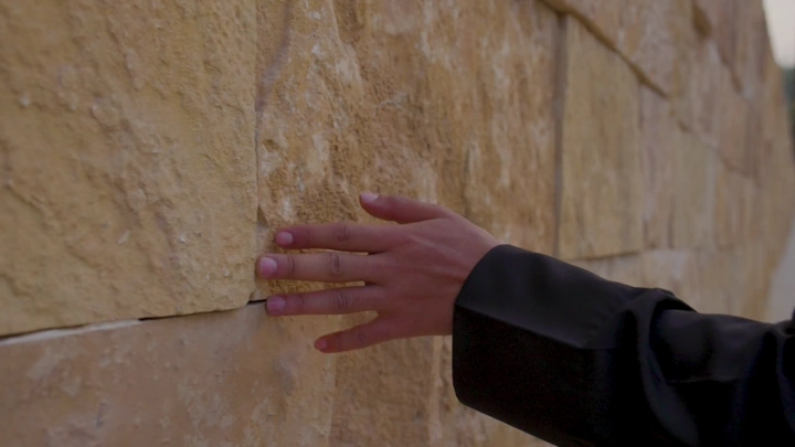 يد تلمس جدار حجري في النهار، لقطة مقربة.
