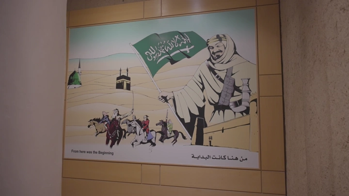 لوحة فنية تاريخية مع شخص واقف بالزي السعودي ليوم التاسيس في قصر المصمك بالرياض، لقطة داخلية.