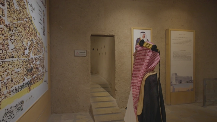 شخص يرتدي الزي التقليدي داخل قصر المصمك في الرياض، لقطة داخلية.