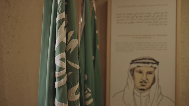 أعلام سعودية بجانب لوحة في قصر المصمك، لقطة داخلية.