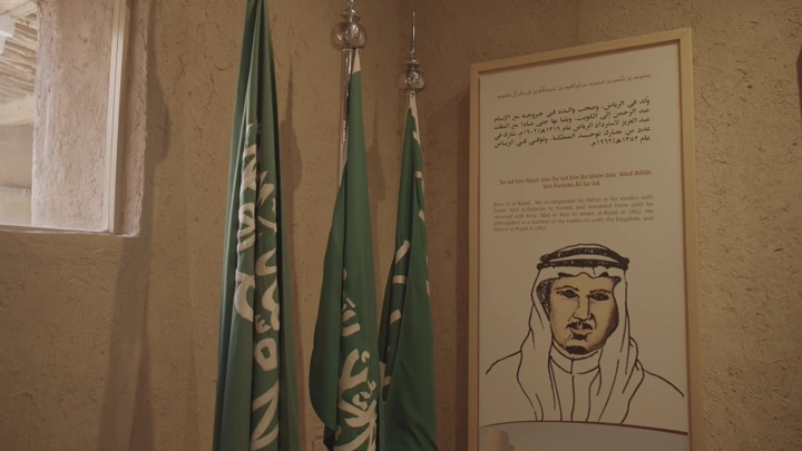أعلام سعودية ولوحة تاريخية داخل قصر المصمك، لقطة داخلية.