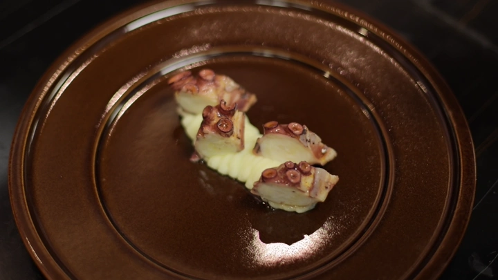 طبق أخطبوط مشوي مع بطاطس مهروسة في مطعم، لقطة قريبة.