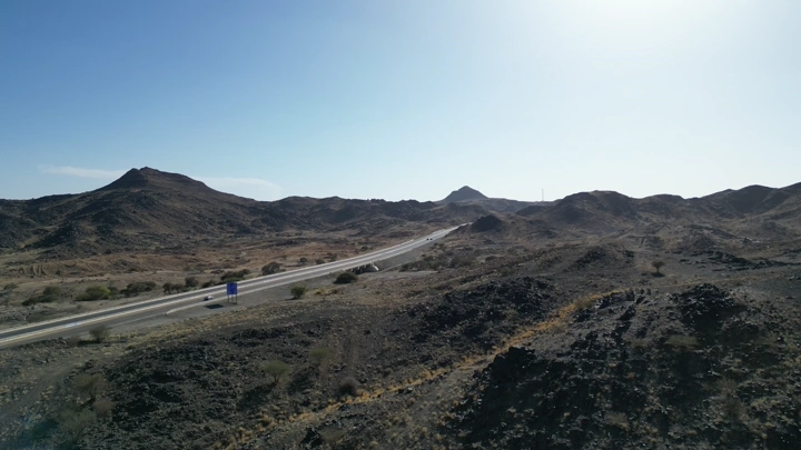 طريق سريع يمر عبر الجبال في وضح النهار، لقطة جوية.