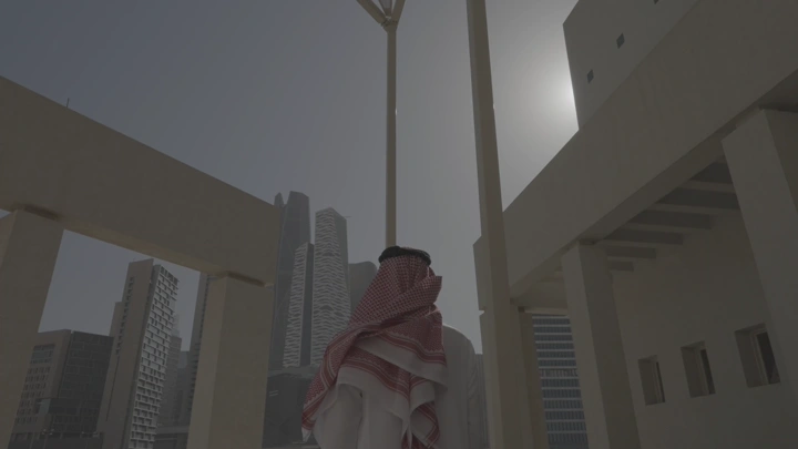 رجل يرتدي الزي التقليدي ينظر إلى أفق الرياض، لقطة من الأسفل.