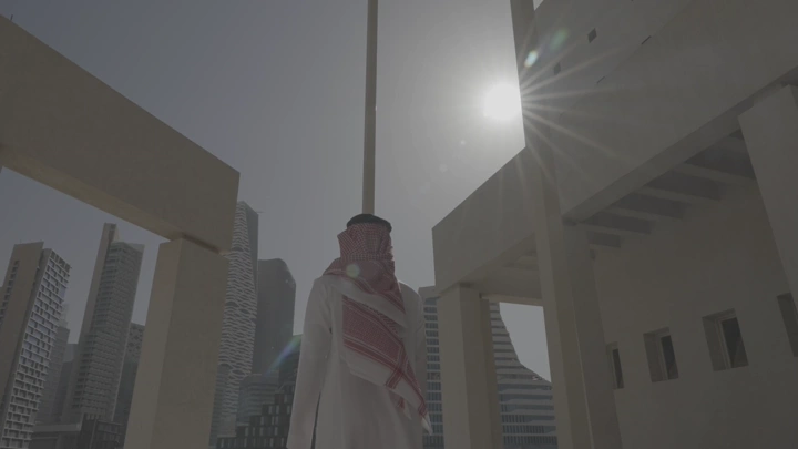 رجل يرتدي الزي التقليدي ينظر إلى أبراج الرياض، لقطة من الأسفل.