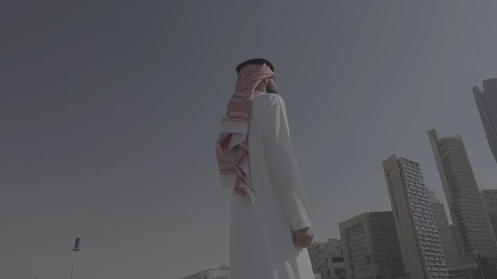 رجل يرتدي الثوب ينظر إلى الأبراج في الرياض، لقطة منخفضة.