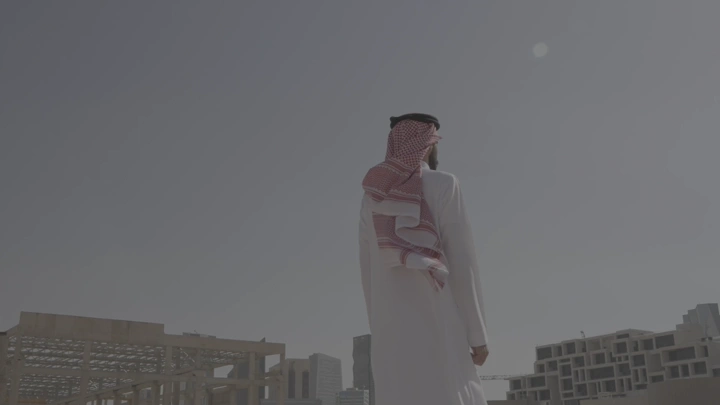 رجل ينظر إلى المدينة المالية في الرياض، لقطة من الخلف.