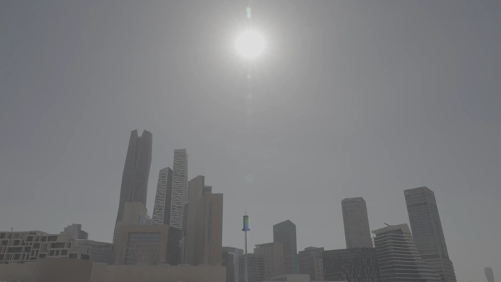 رجل ينظر إلى ناطحات سحاب في الرياض تحت الشمس الساطعة، لقطة نهارية.