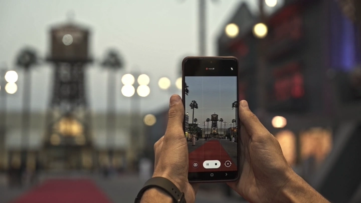 يد تمسك هاتفًا يصور البوليفارد في الرياض، لقطة قريبة.