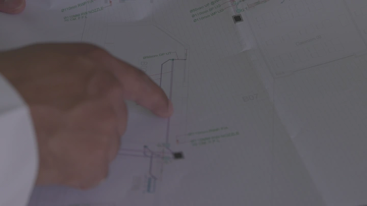 شخص يشير إلى مخطط معماري على طاولة، لقطة قريبة.