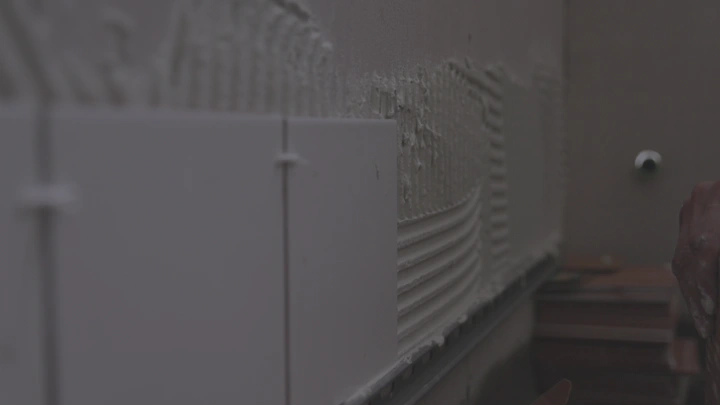 تركيب بلاط على جدار في موقع بناء، لقطة قريبة.