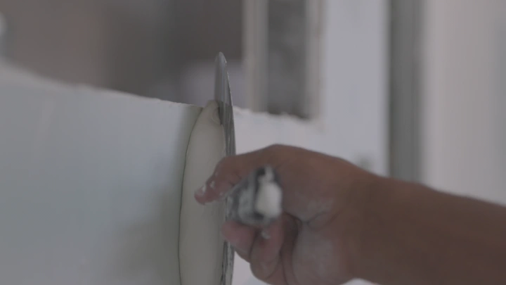 يد تضع المعجون على الحائط، لقطة قريبة.