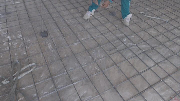 عامل يربط شبكة حديدية في موقع بناء، لقطة قريبة.