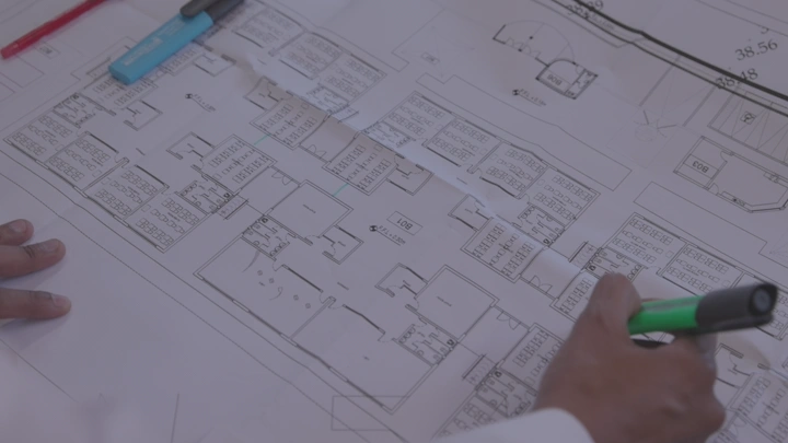 شخص يراجع مخطط معماري على طاولة، لقطة مقربة.