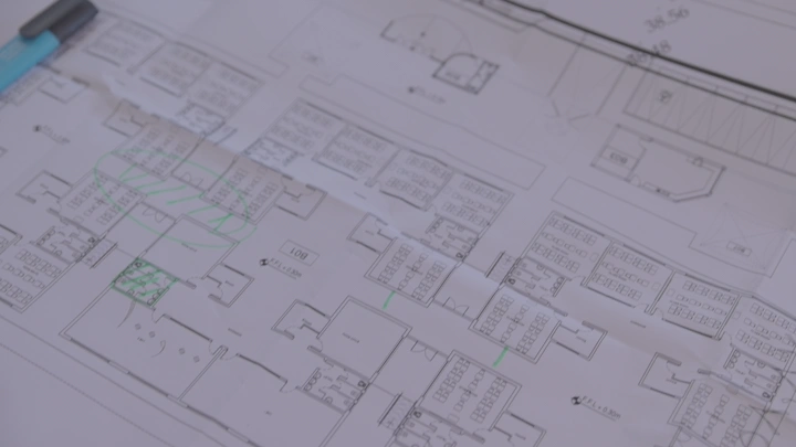 مخطط معماري على طاولة مع قلم أزرق، لقطة قريبة.
