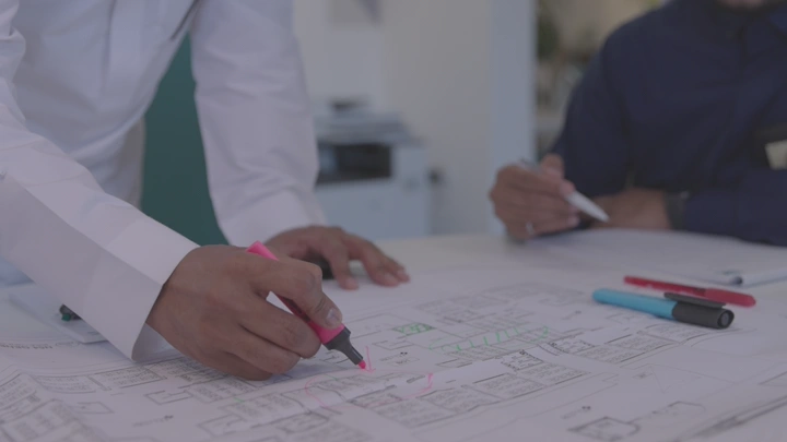 شخص يراجع مخطط معماري على طاولة، لقطة مقربة.