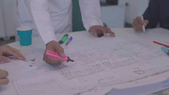 شخص يراجع مخطط معماري على طاولة، لقطة قريبة.