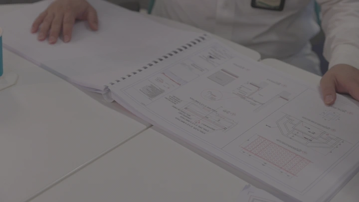 شخص يراجع مخطط معماري على طاولة، لقطة قريبة.