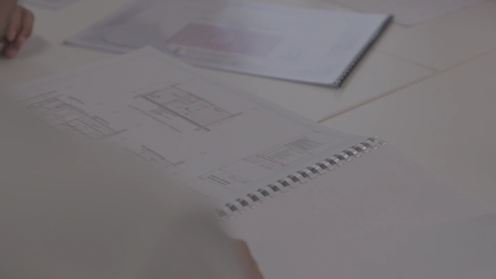 شخص يراجع مخطط معماري على طاولة، لقطة مقربة.