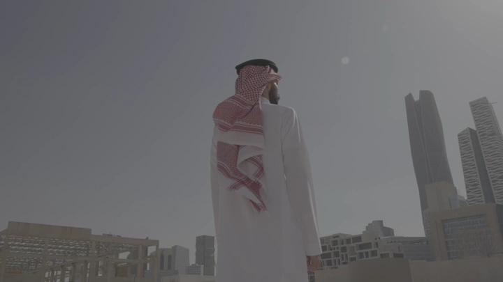رجل ينظر إلى أفق المدينة المالية في الرياض، لقطة من الخلف.