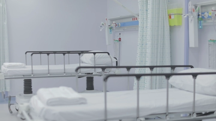 أسرة مستشفى بيضاء في غرفة فارغة، لقطة داخلية.