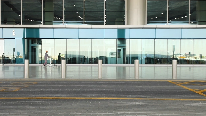واجهة مطار حديثة مع شخص يسحب عربة، لقطة أمامية.
