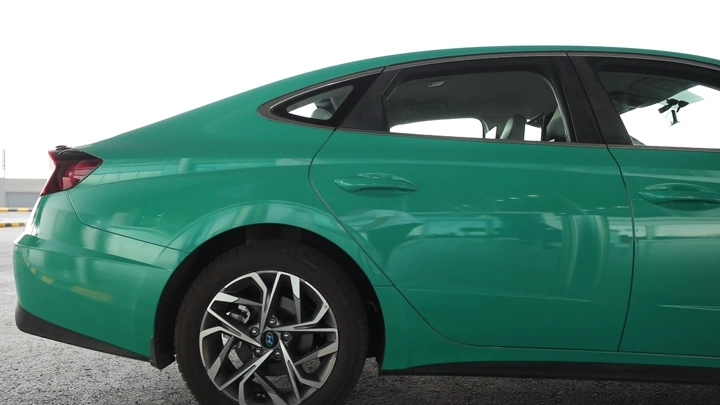 سيارة أجرة خضراء في موقف سيارات مع شخص يركب، لقطة جانبية.