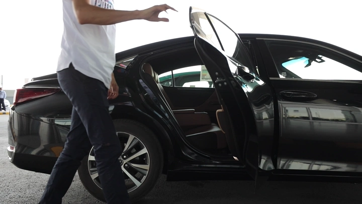 رجل يفتح باب سيارة ويركب في الداخل سيارة سوداء في موقف سيارات، لقطة جانبية.